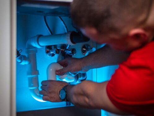 A plumber repairs the pipes beneath a sink, demonstrating services offered by a Winter Haven plumber