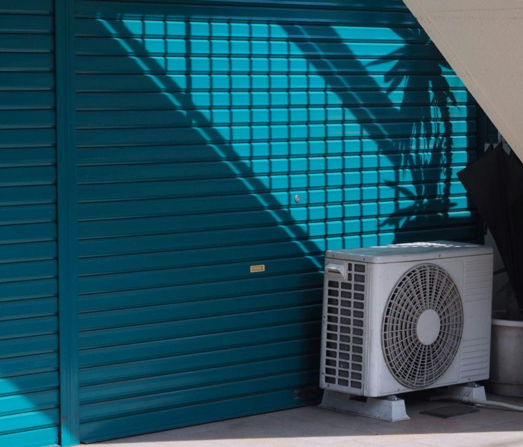 An outdoor AC condenser beside a garage highlights the importance of maintaining efficient cooling equipment.